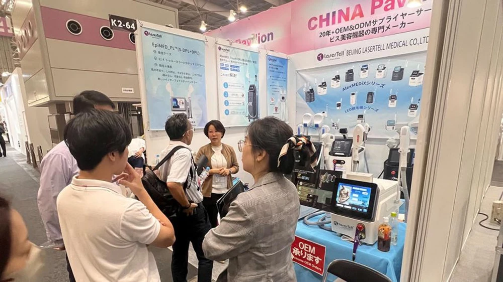 LaserTell staff discussing medical aesthetic machines and OEM ODM services with visitors at COSME OSAKA